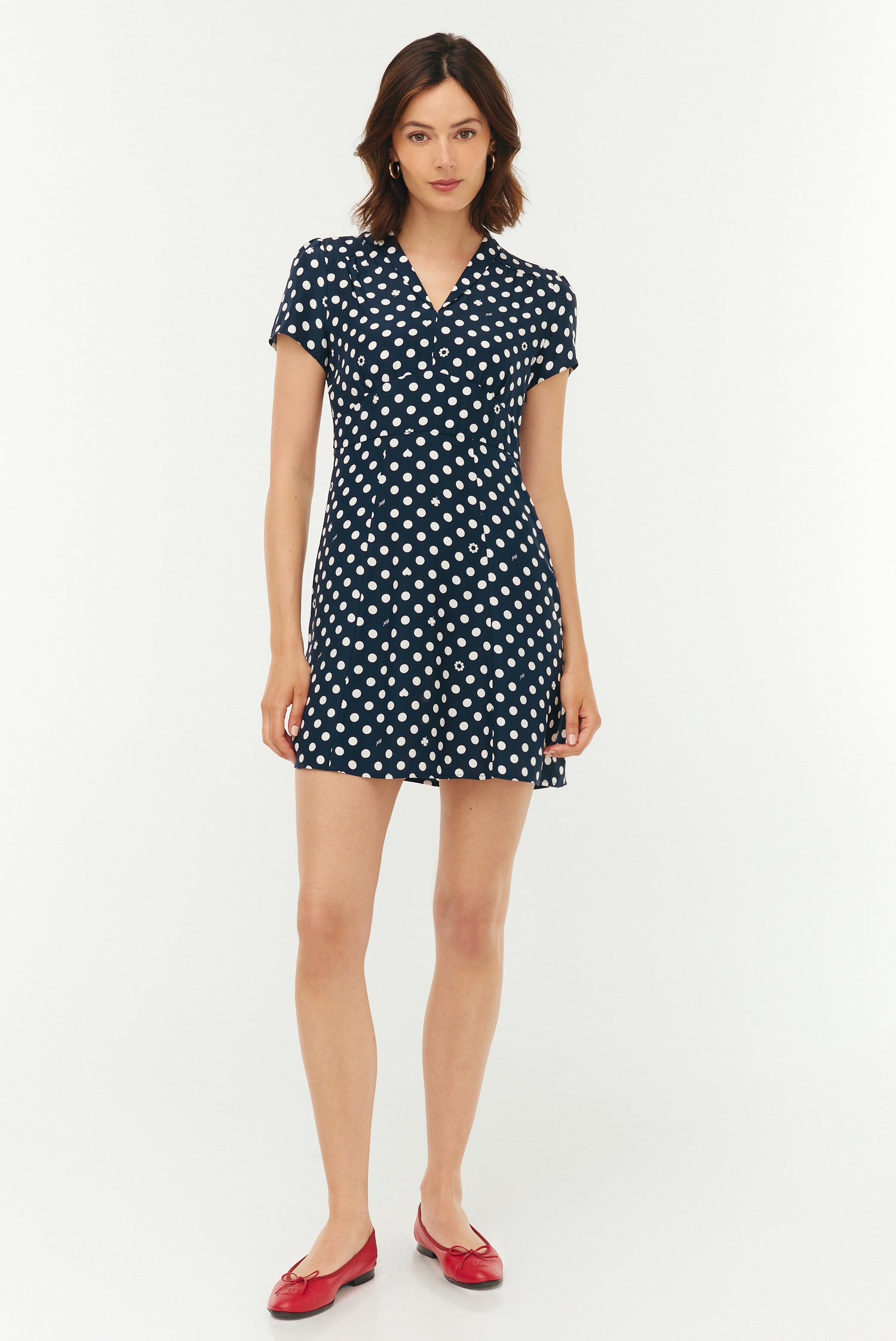 Woman wearing a navy dress with white polka dots on a white background