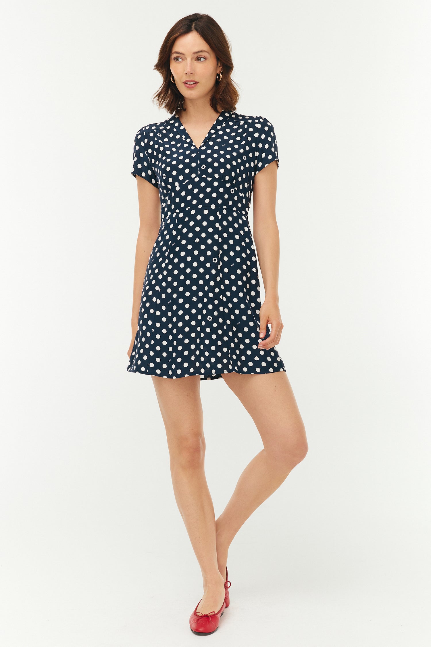 Woman wearing a navy dress with white polka dots on a white background