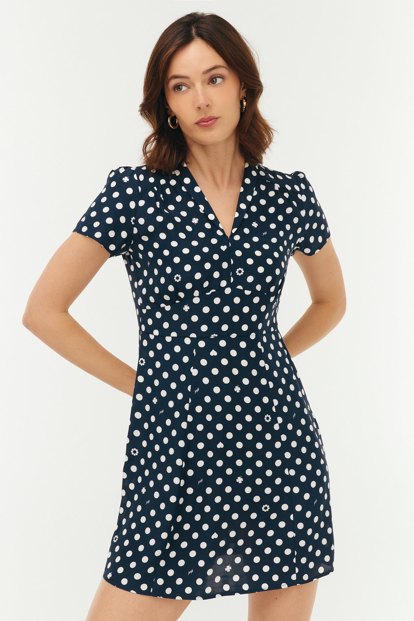 Woman wearing a navy dress with white polka dots on a white background