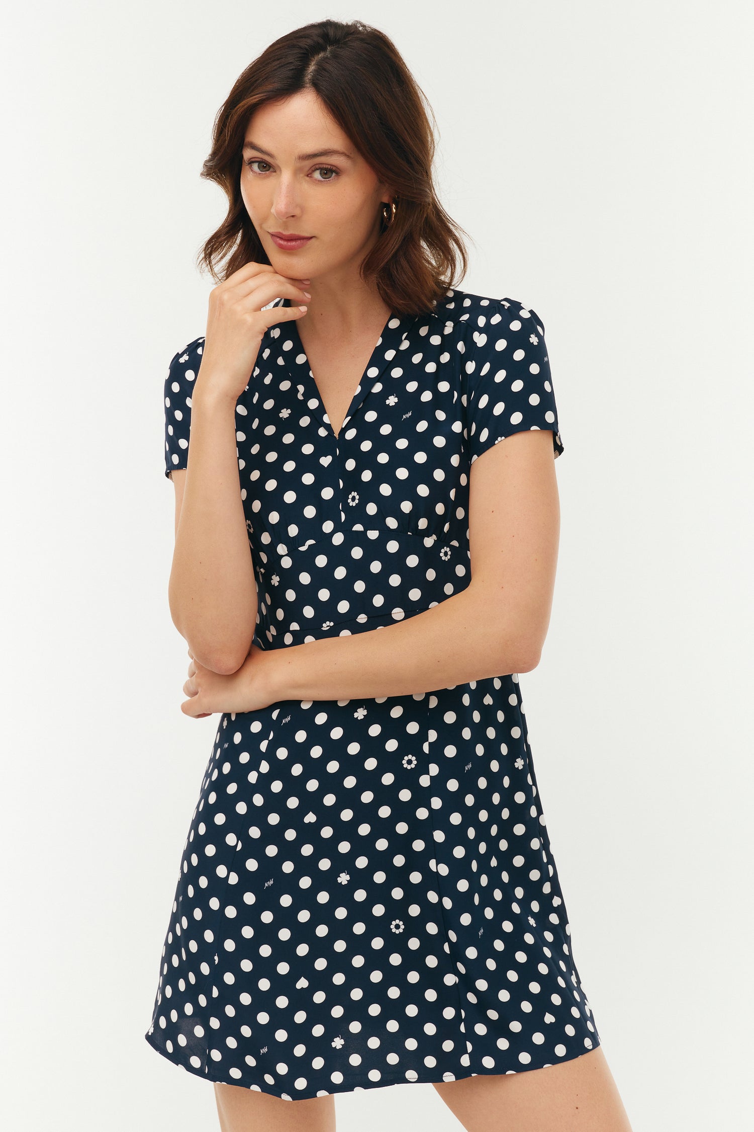 Woman wearing a navy dress with white polka dots on a white background