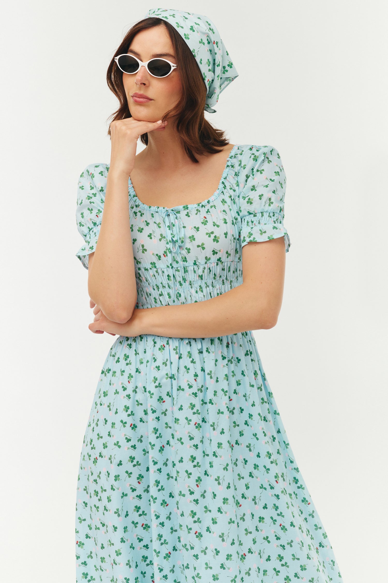 Woman wearing a light blue floral dress and headscarf on a white background