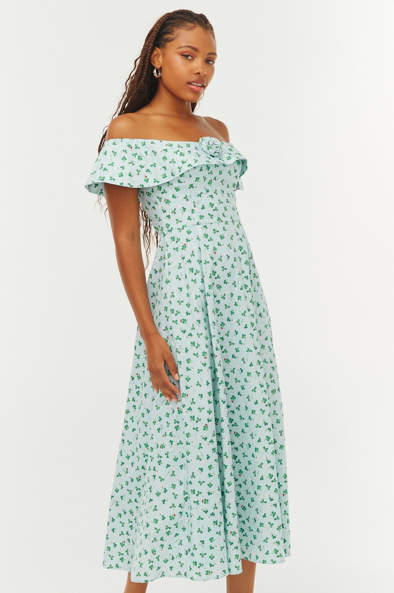 Woman wearing a green floral off-shoulder dress on a white background