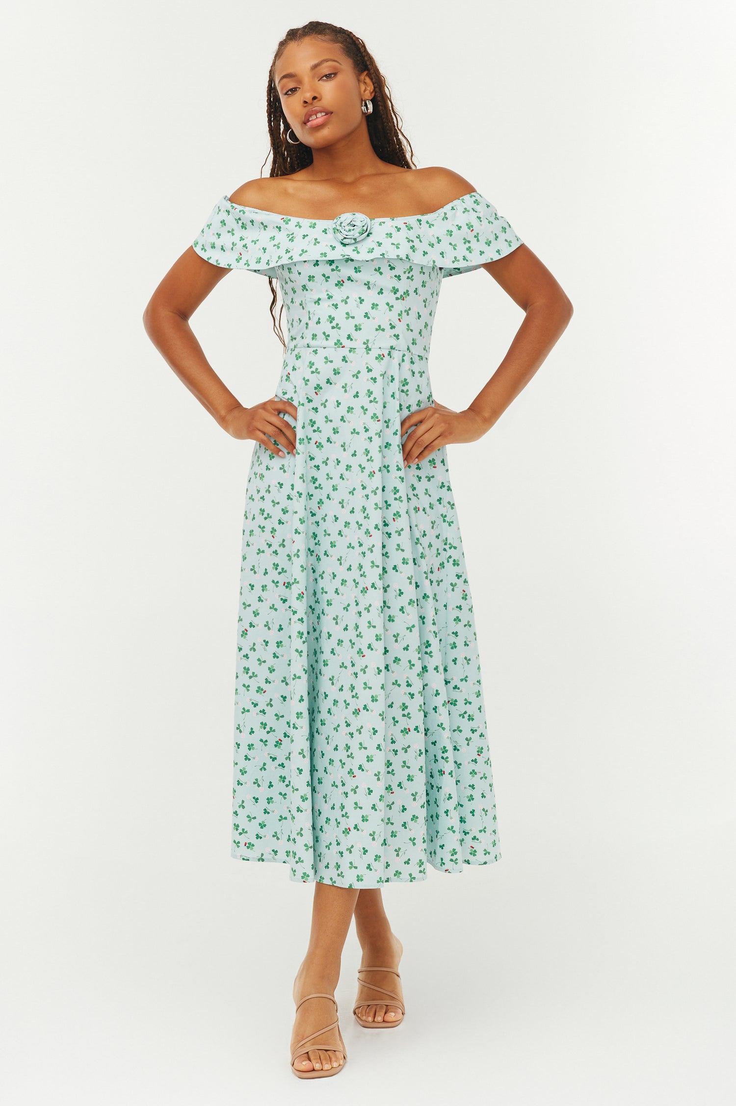 Woman wearing a green floral off-shoulder dress on a white background