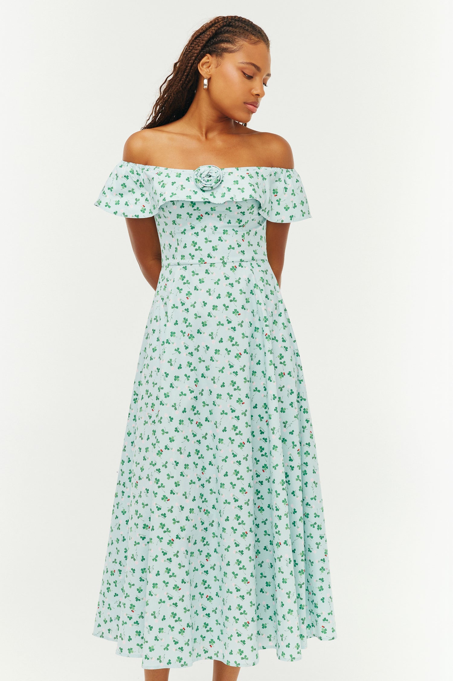 Woman wearing a green floral off-shoulder dress on a white background