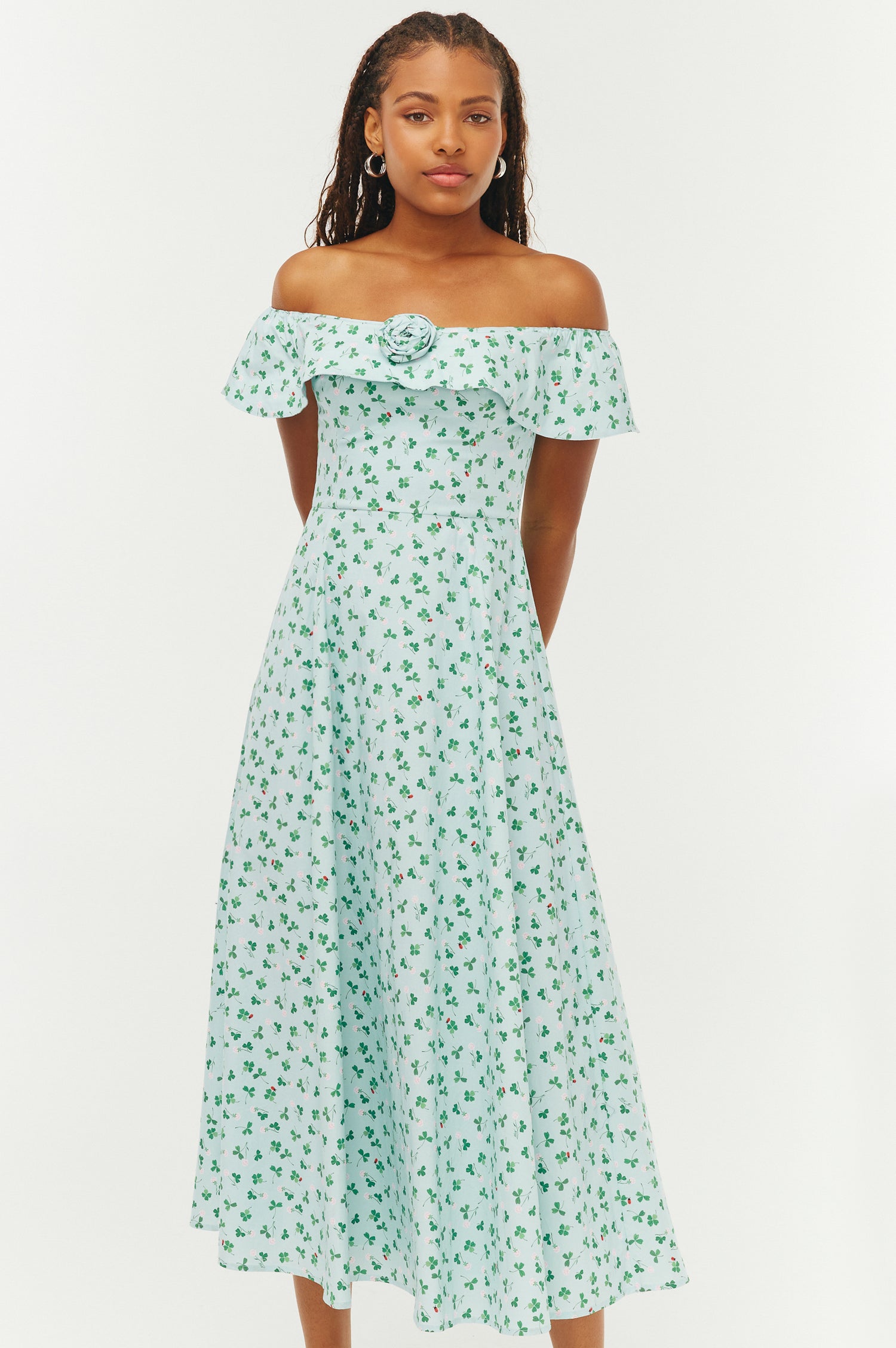 Woman wearing a green floral off-shoulder dress on a white background