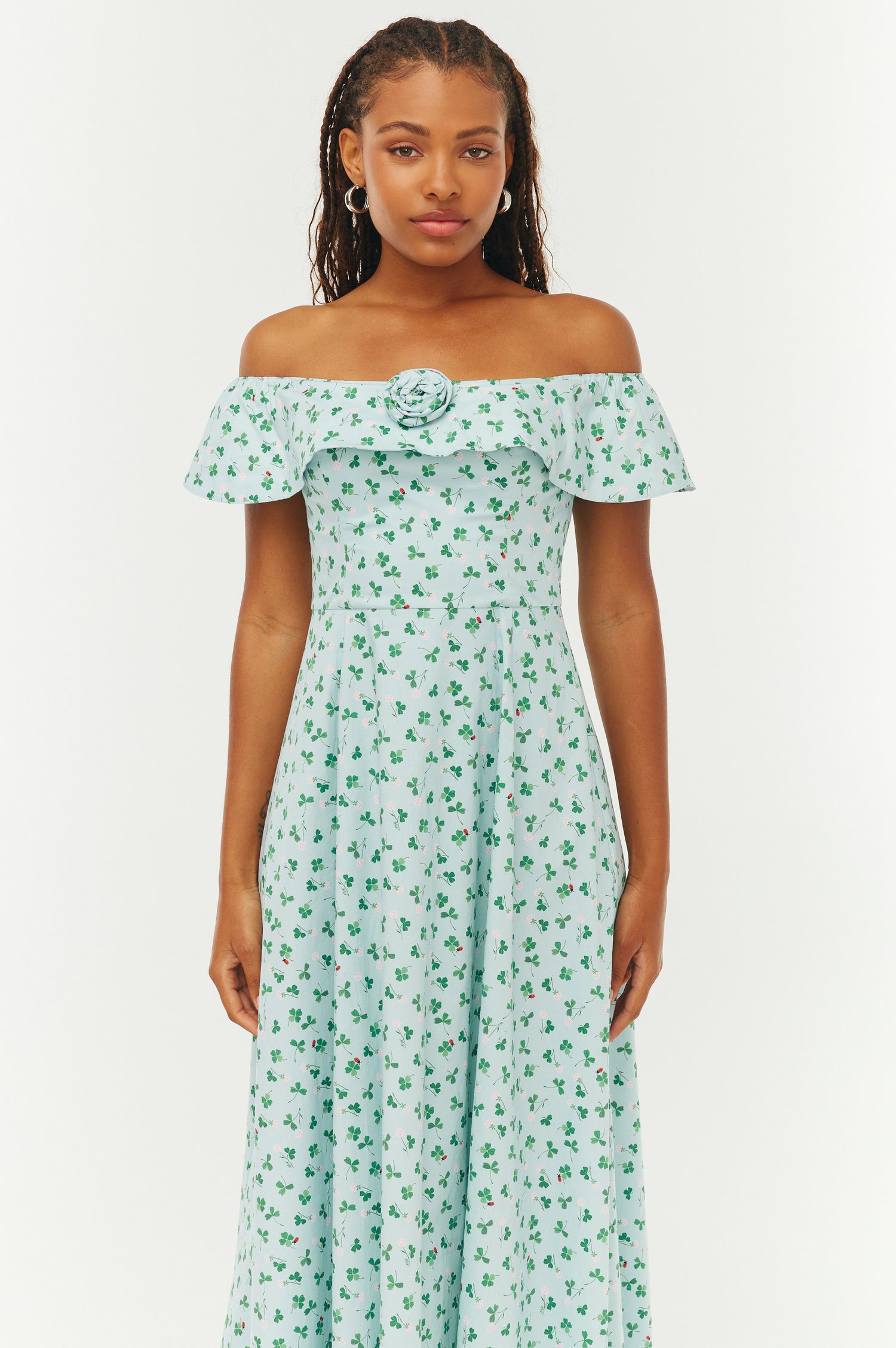 Woman wearing a green floral off-shoulder dress on a white background