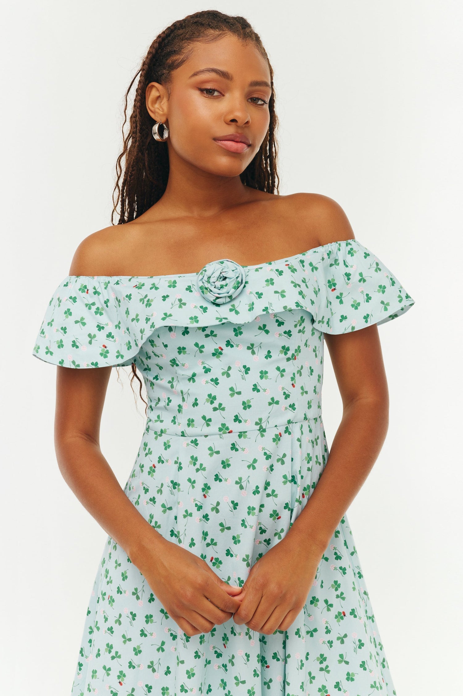 Woman wearing a green floral off-shoulder dress on a white background