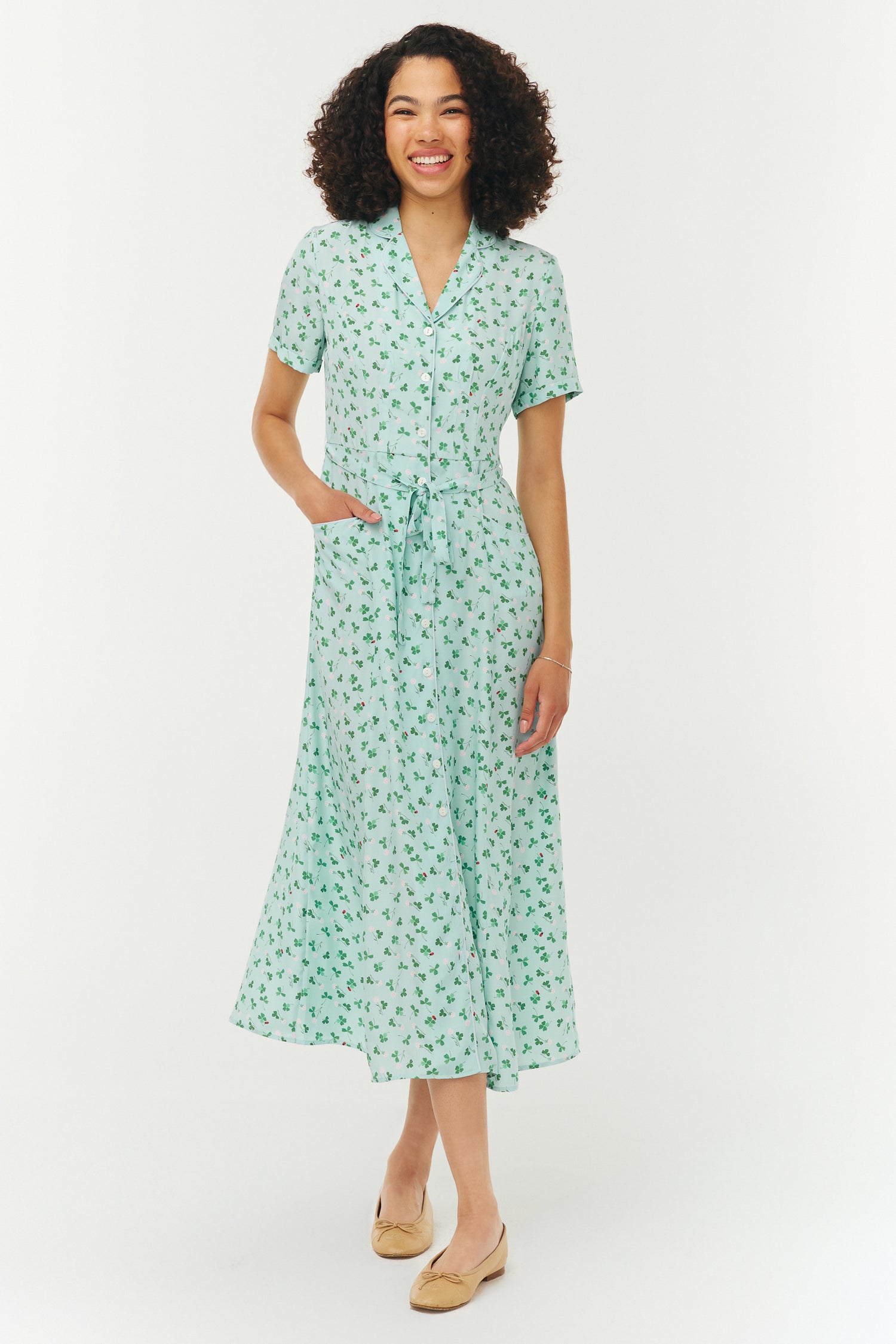 Woman wearing a light blue and green floral dress on a white background