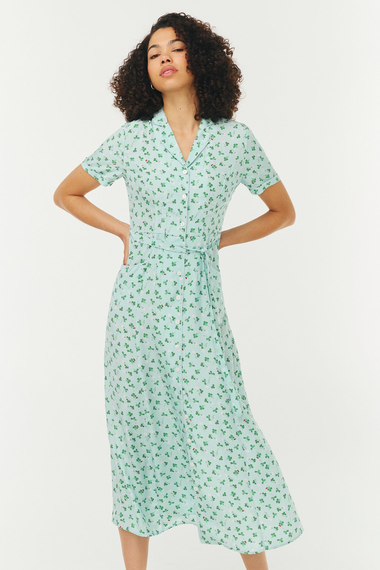 Woman wearing a light blue and green floral dress on a white background