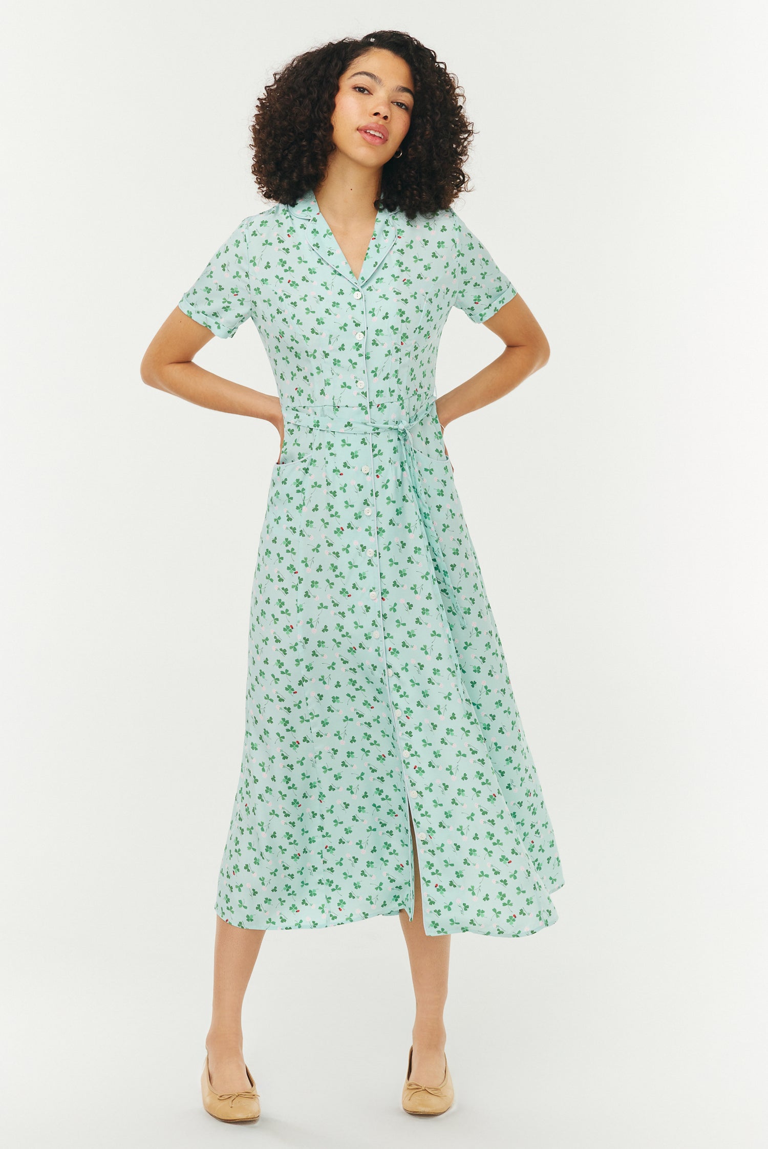 Woman wearing a light blue and green floral dress on a white background