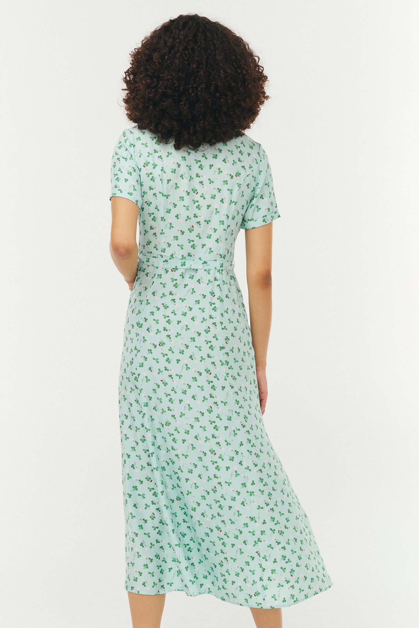 Woman wearing a light blue and green floral dress on a white background