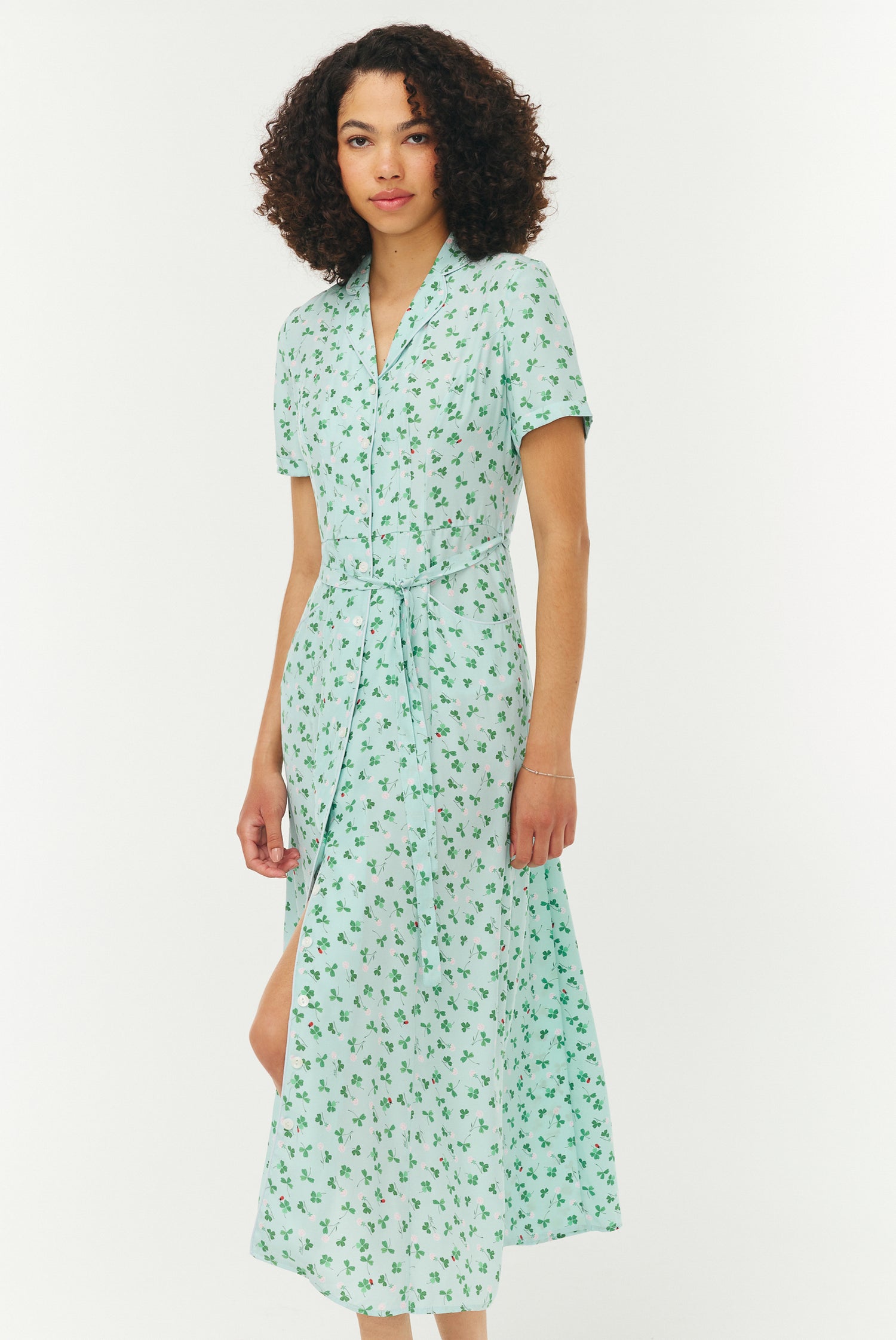 Woman wearing a light blue and green floral dress on a white background