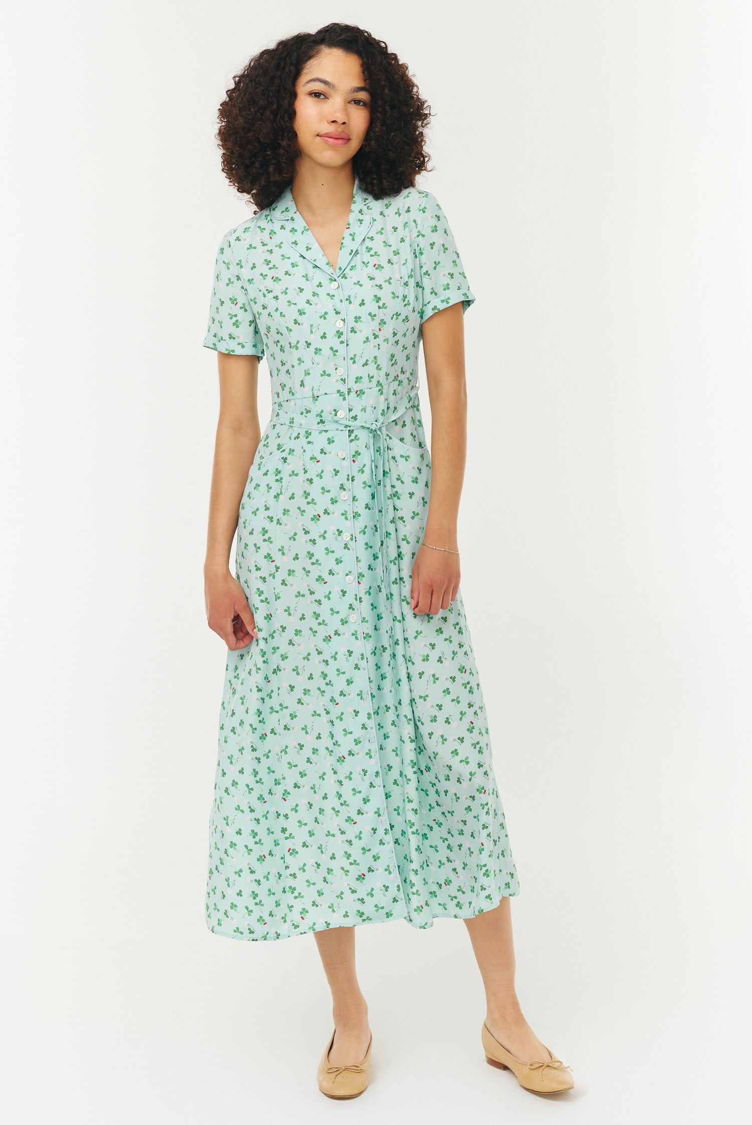 Woman wearing a light blue and green floral dress on a white background