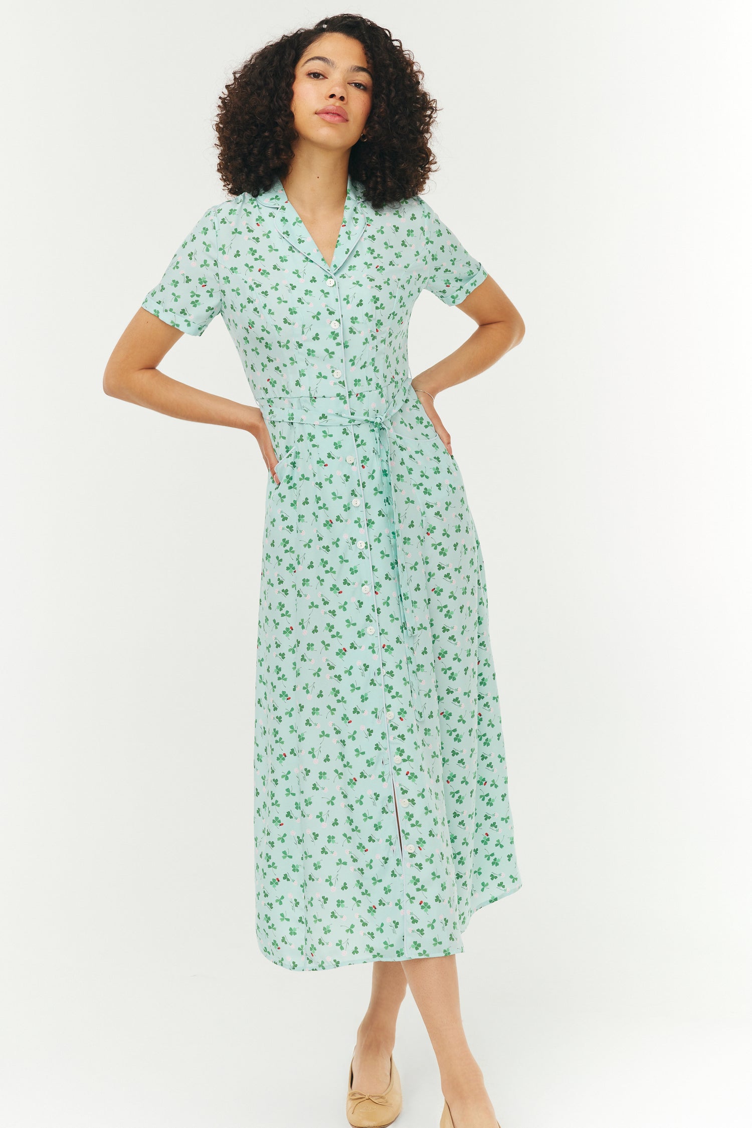 Woman wearing a light blue and green floral dress on a white background
