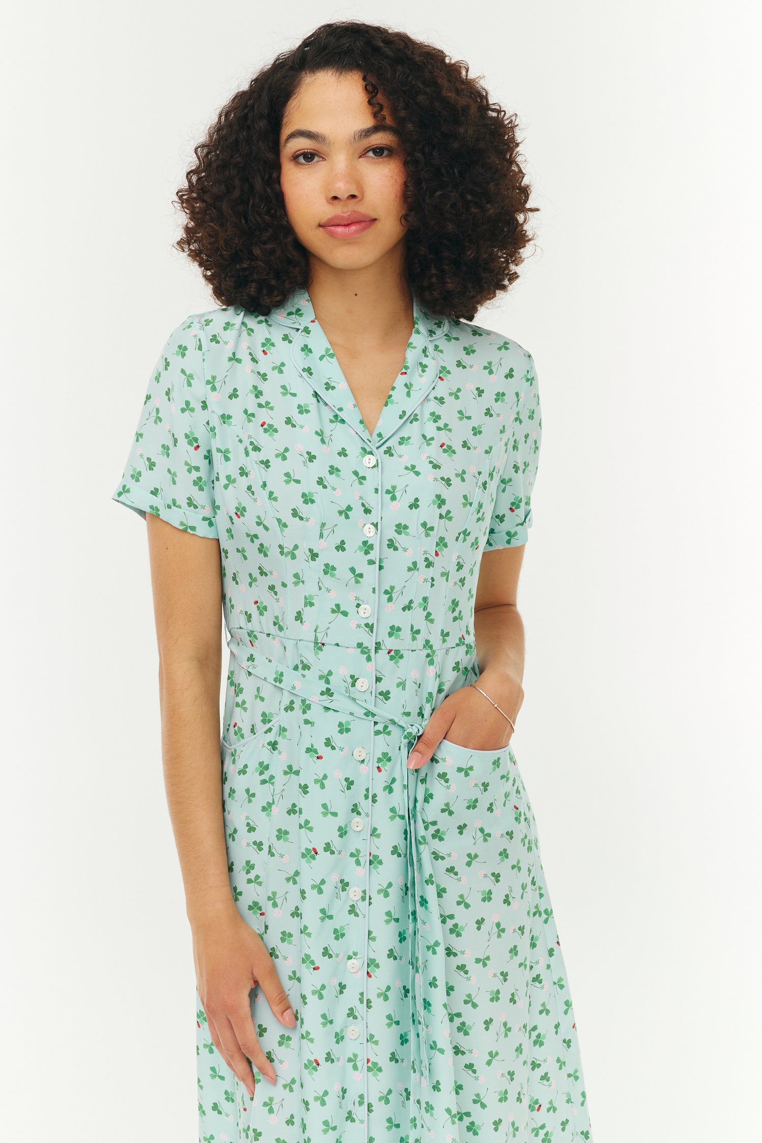 Woman wearing a light blue and green floral dress on a white background
