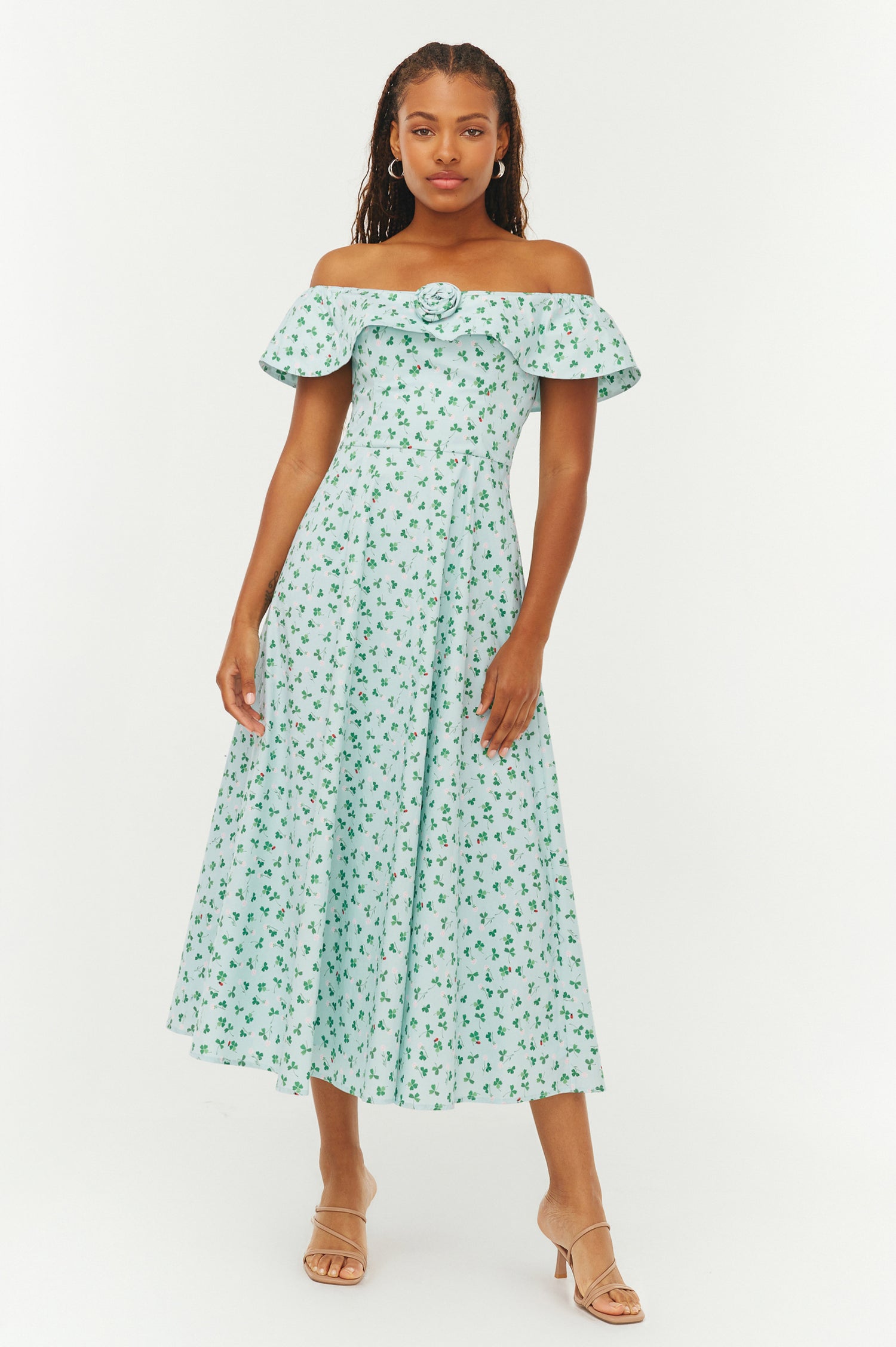 Woman wearing a green floral off-shoulder dress on a white background