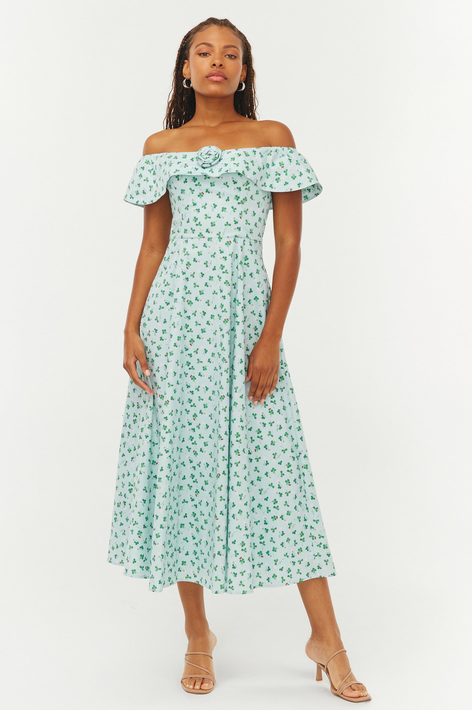 Woman wearing a green floral off-shoulder dress on a white background