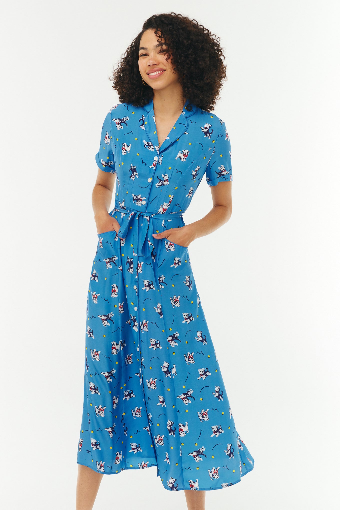 Woman wearing a blue dress with cartoon dog print on a white background.