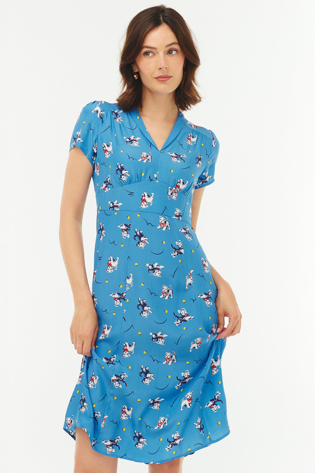 Woman wearing a blue dress with cartoon dog print on a white background.