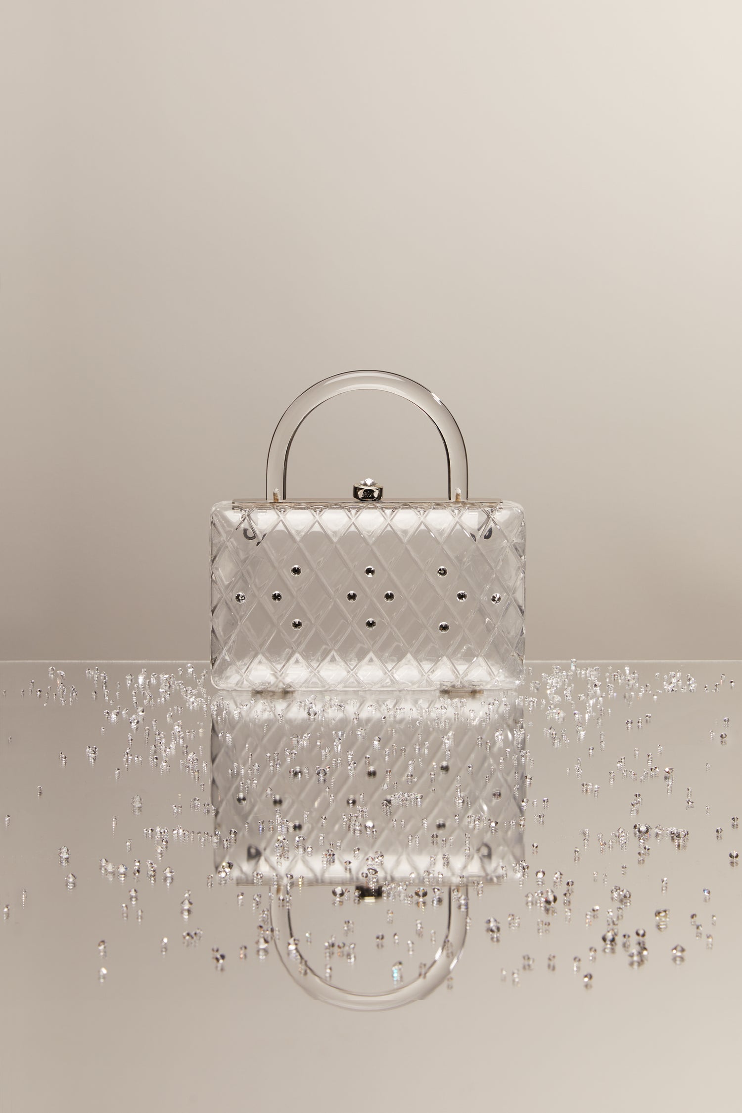 A clear acrylic handbag with crystals and a short handle. 