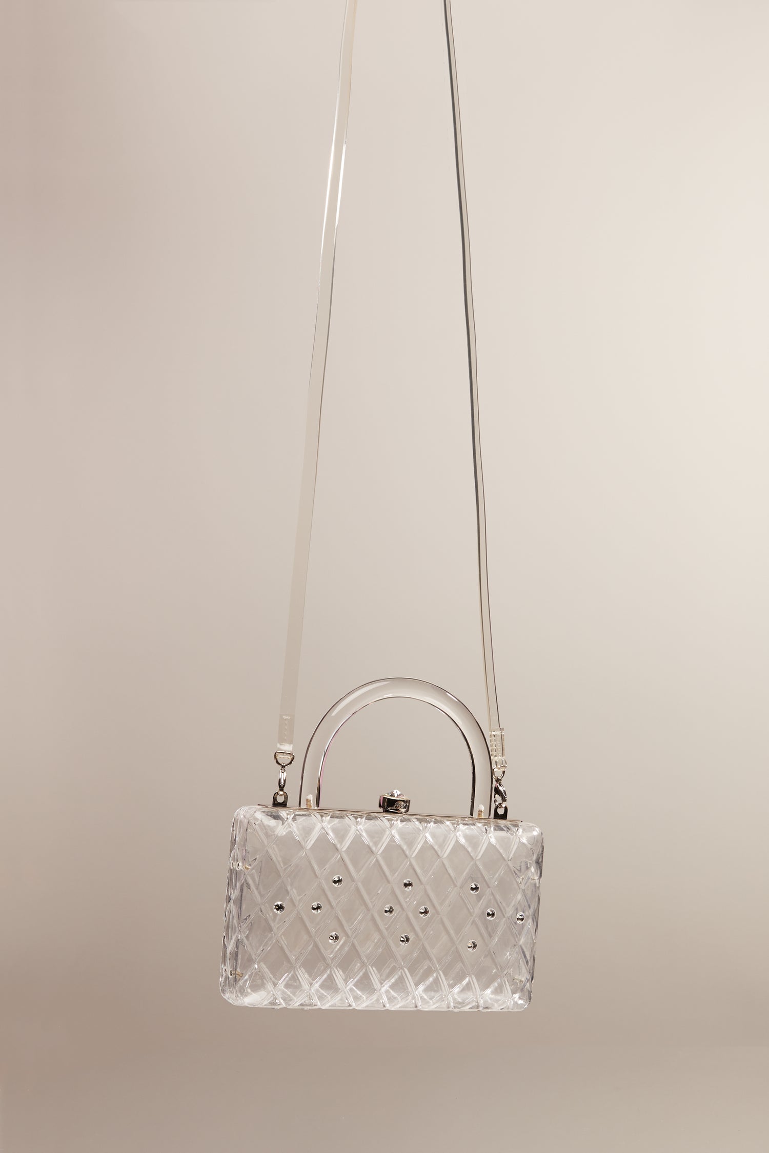 A clear acrylic handbag with crystals and a short handle with a long clear strap. 