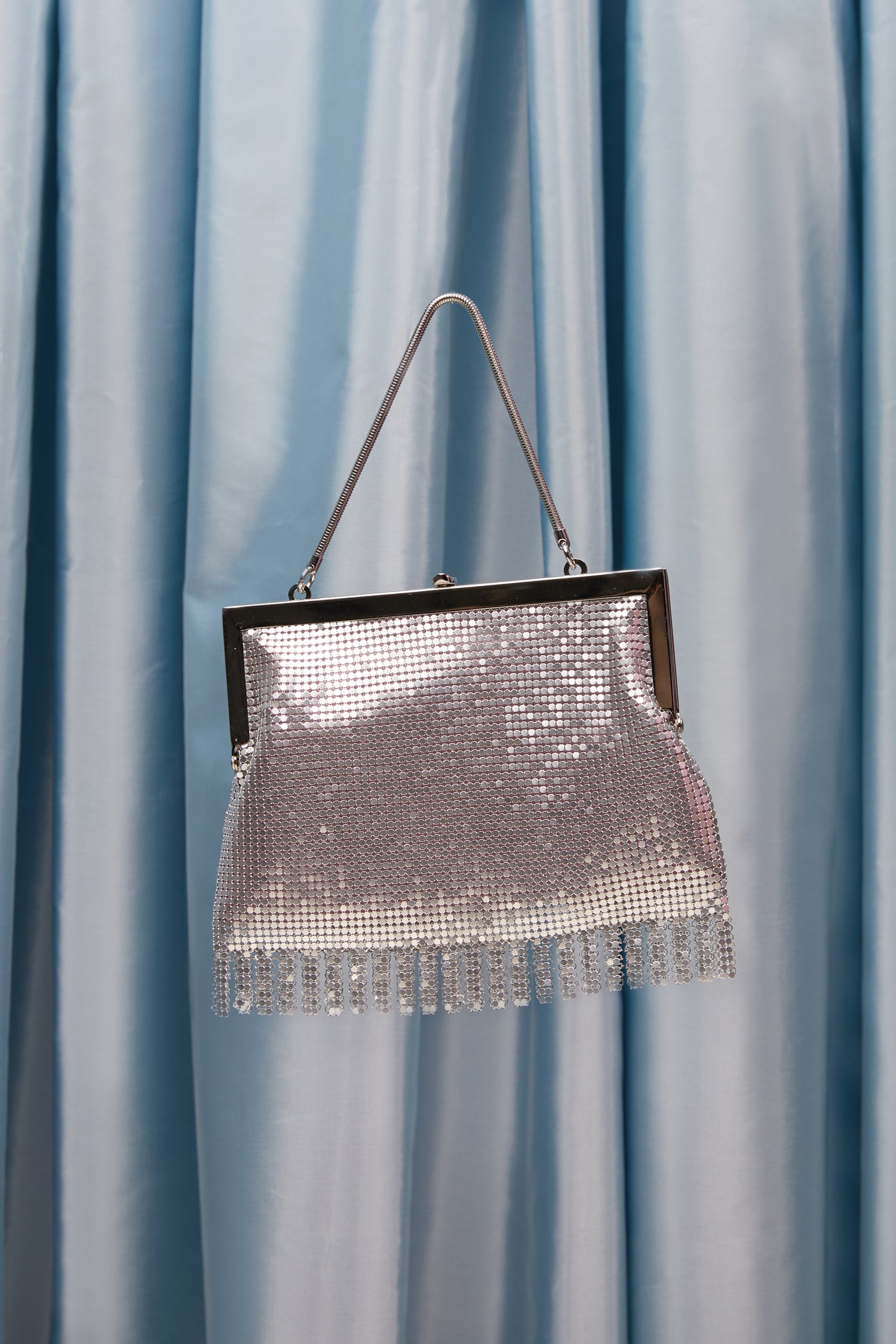 A small, silver chainmail bag with a silver chain handle. 