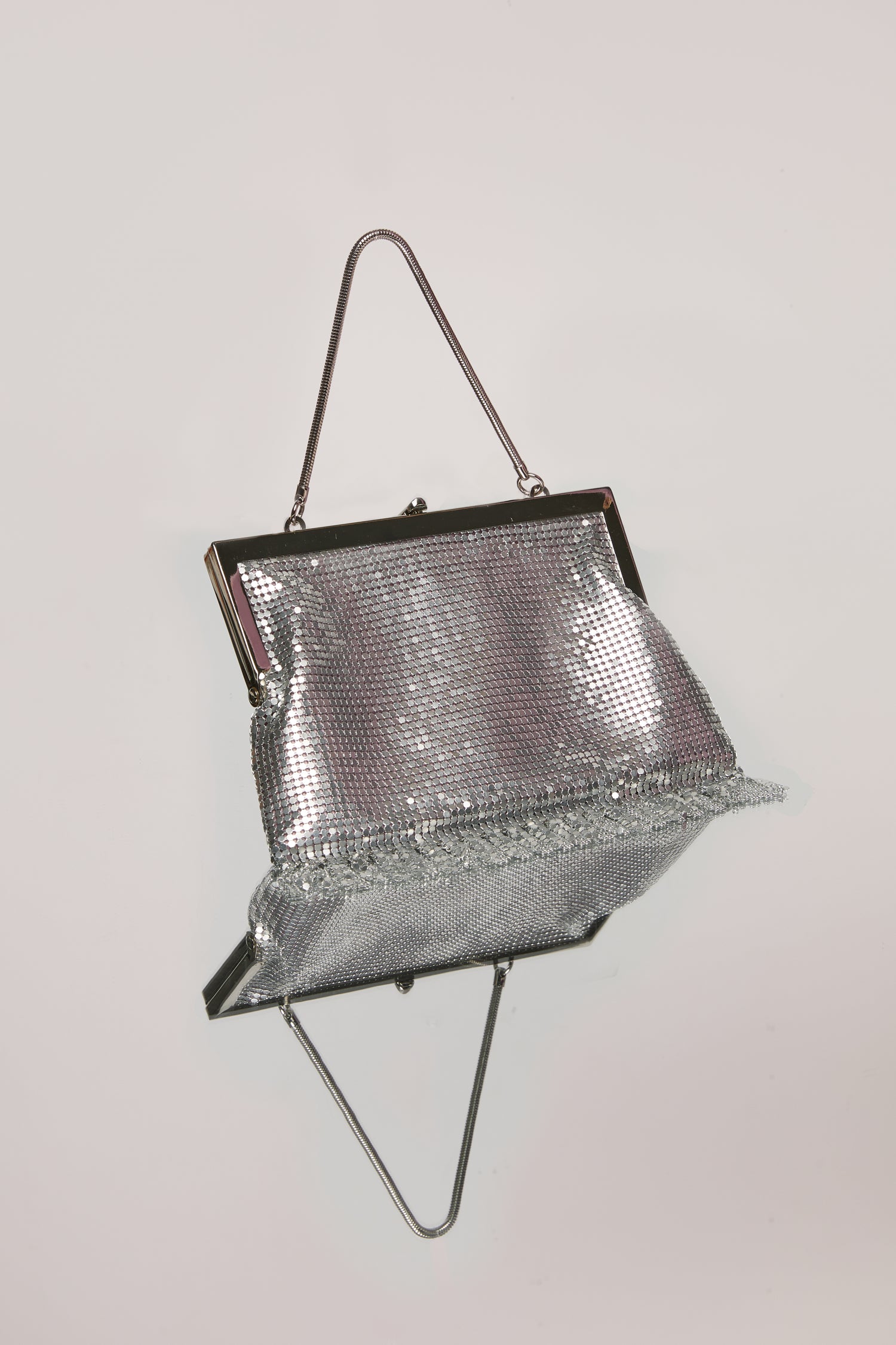 A small, silver chainmail bag with a silver chain handle. 