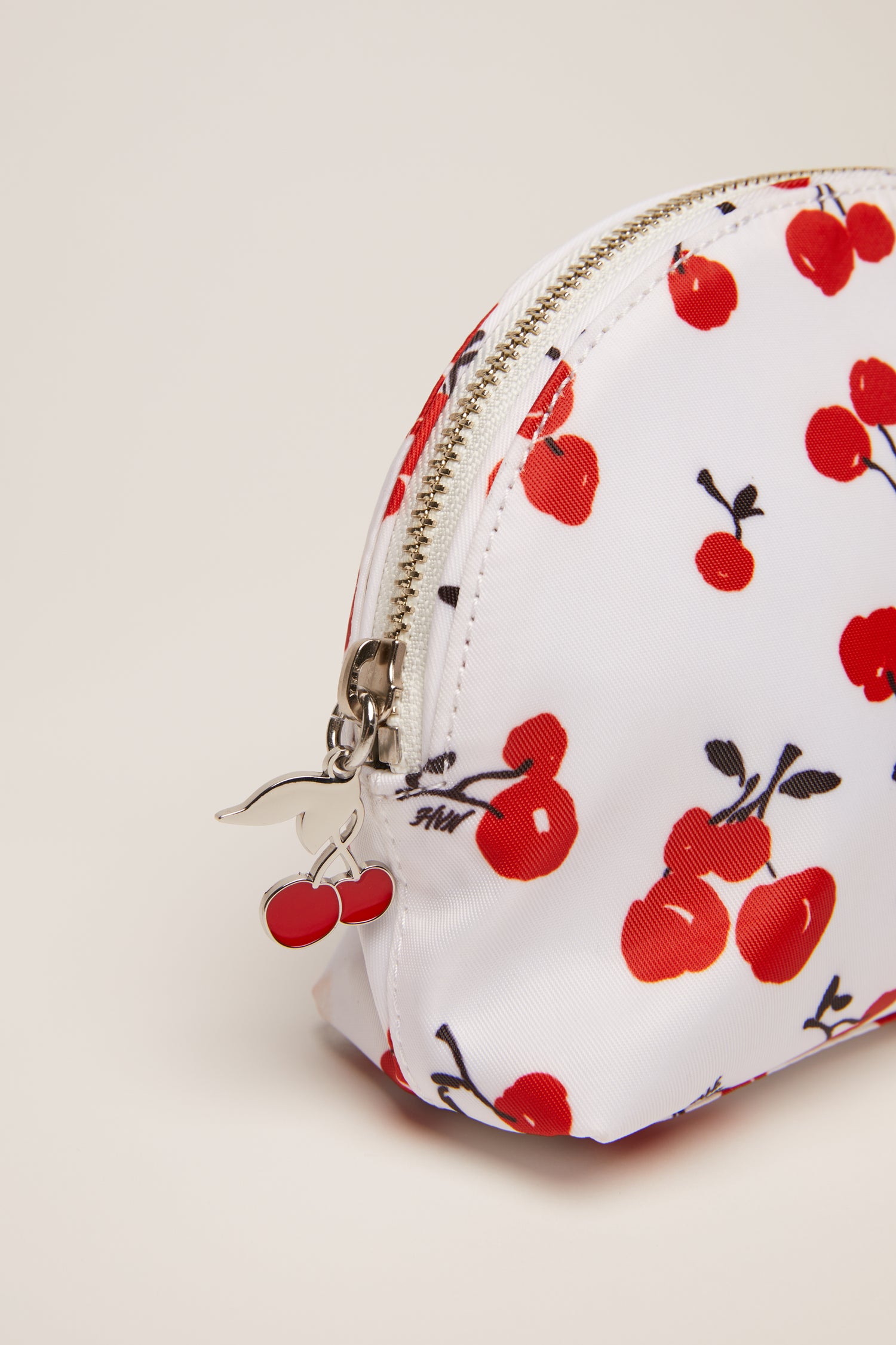 A cherry print cosmetic case with a cherry zip pull. 