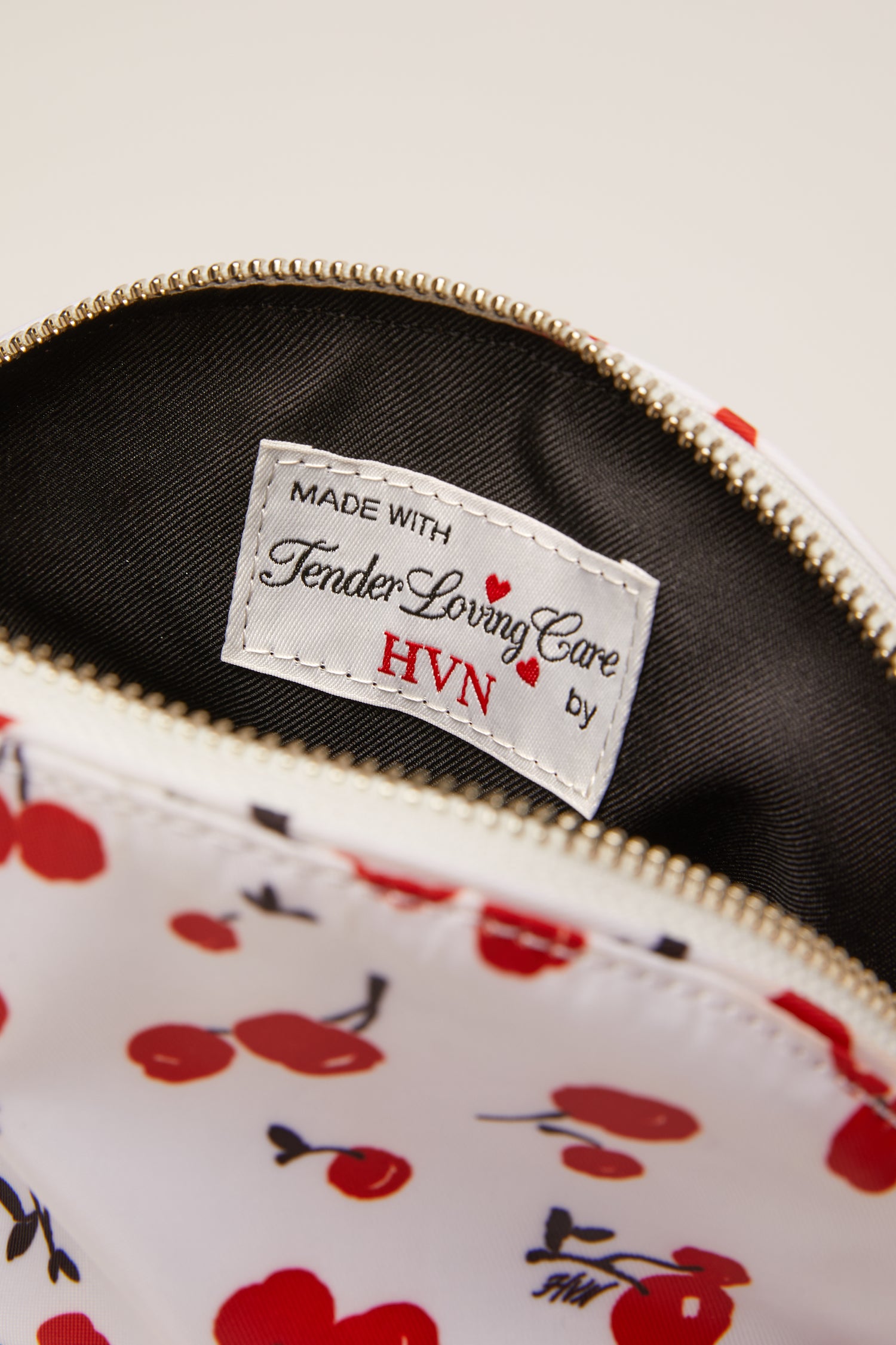 A cherry print cosmetic case with a cherry zip pull. 