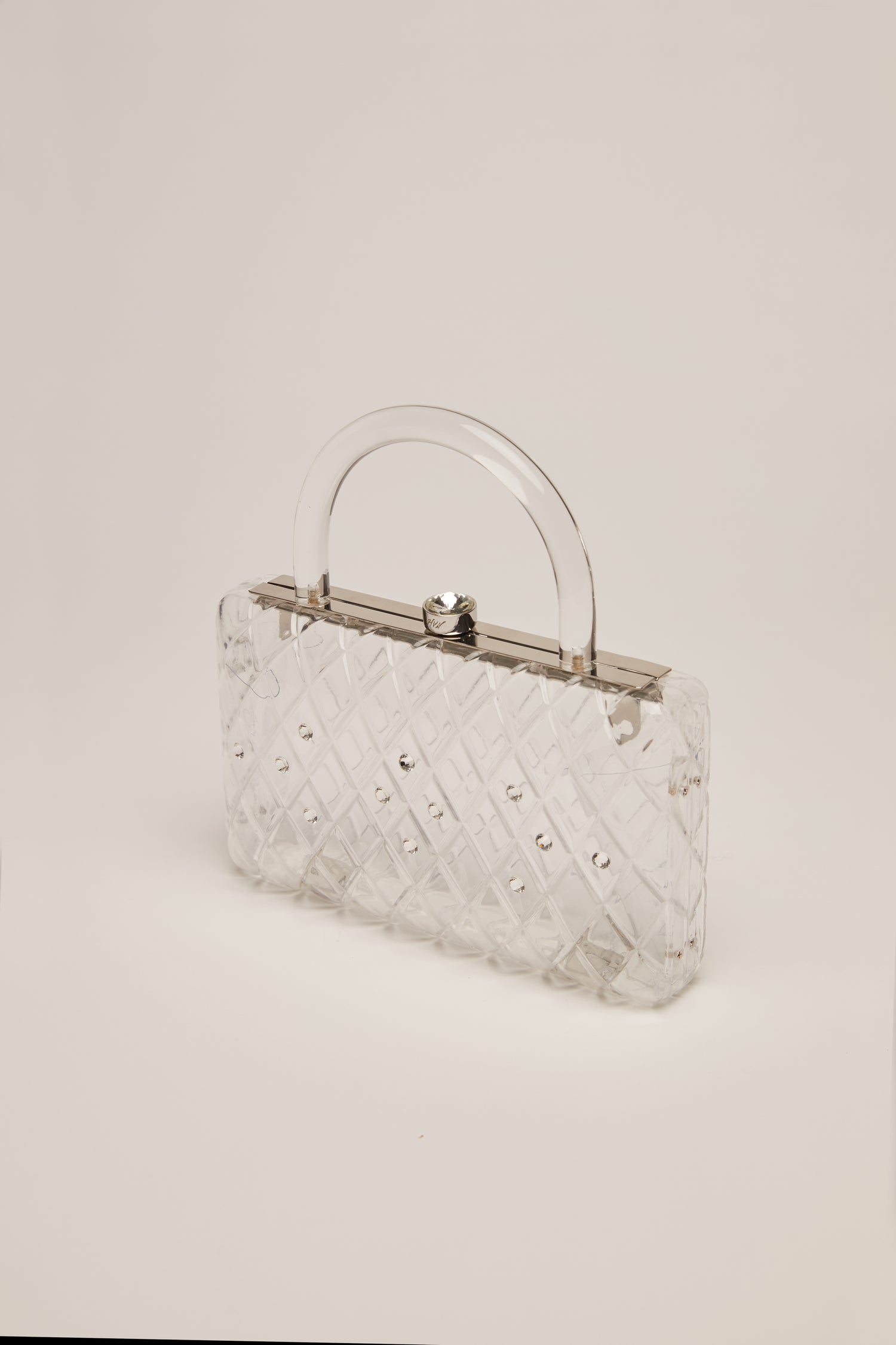 A clear acrylic handbag with crystals and a short handle. 